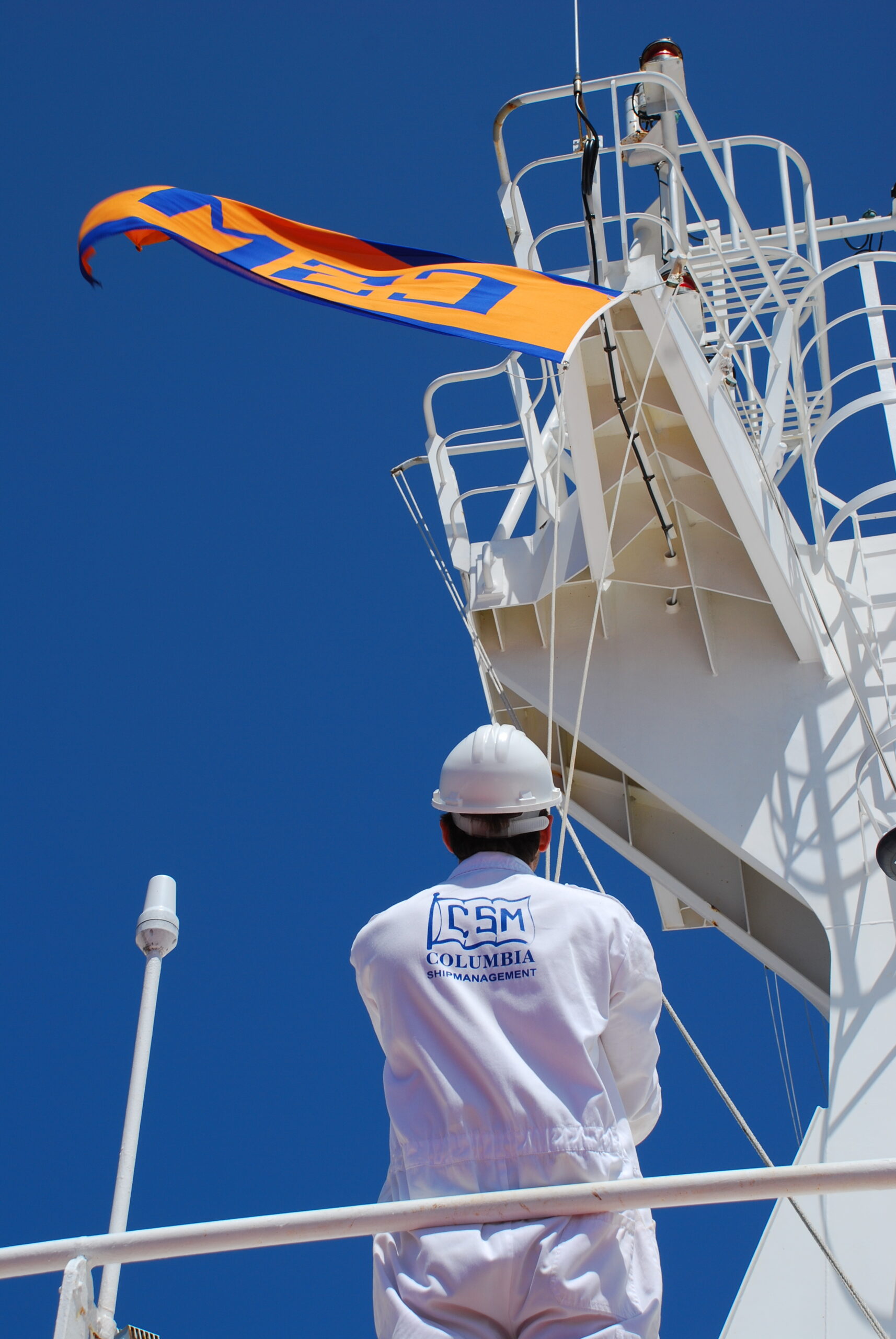 Seafarer beneath a Columbia Shipmanagement flag